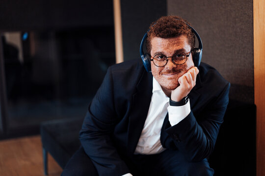 A businessman with a freckle listens to music at the office