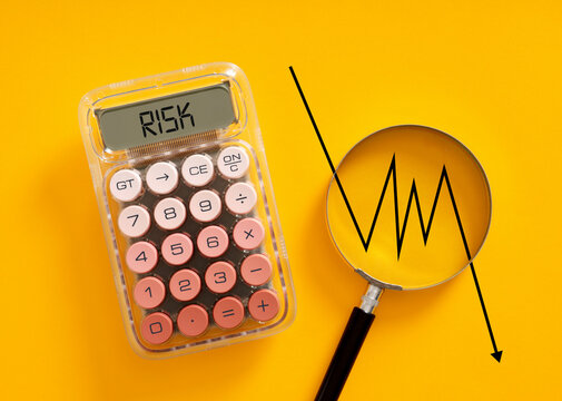 Calculator showing risk with declining graph and magnifying glass