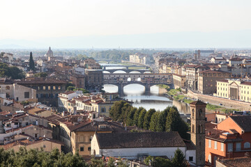 Fototapeta premium Elevated panoramic view of Ponte Vecchio crossing the Arno River in Florence, Tuscany, Italy, photographed in warm afternoon light with historic architecture and city skyline.