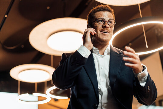 A smiling businessman talks on a smartphone in a modern office