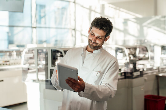 Smiling scientist holding a tablet in a modern laboratory