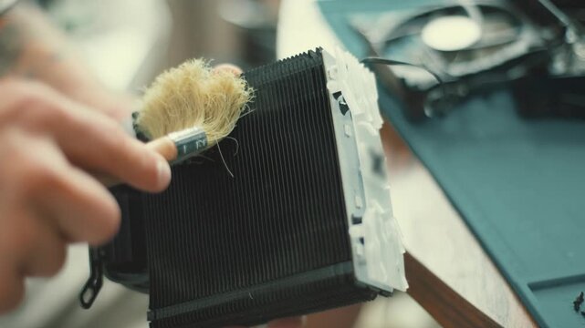 Cleaning a computer part with a brush in a workshop setting in daylight
