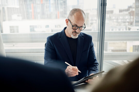 Businessman writes on a tablet computer in a modern London office
