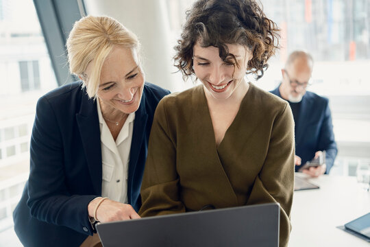 Smiling businesswomen working on laptop in modern London office