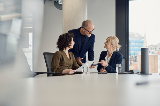 Business colleagues discuss work in a modern London office boardroom