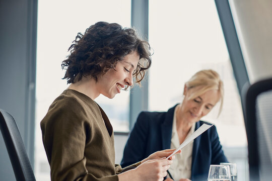 Smiling businesswoman reads document during an office meeting