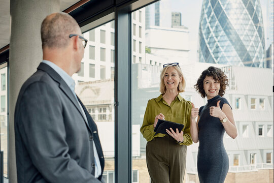 Businessman and businesswoman discuss work in a London office