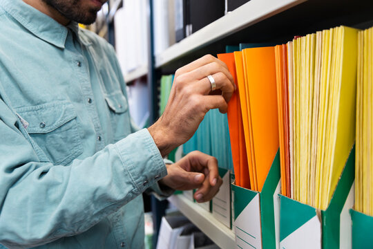 Man searches for document in colorful folders at the office