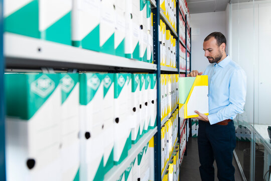 Businessman searches for paperwork in an office archive