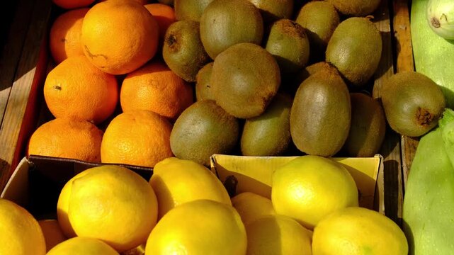 oranges and kiwis at the market. Fresh Oranges, Lemons and Kiwis in Plastic Crates at an Outdoor Farmer Market