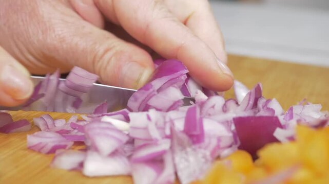 A fresh onion is sliced to reveal its layered structure on the cutting board, the translucent rings catching the light as they are prepared for the classic Italian soffritto cooking base.