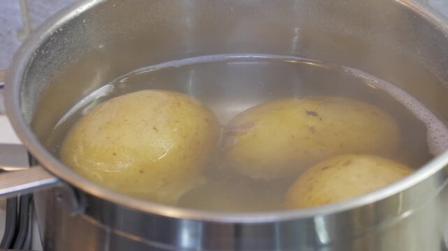 Potatoes bubble and cook in a pot of boiling water on a home kitchen stove, a simple and comforting everyday cooking moment rooted in the warmth of Italian domestic life.