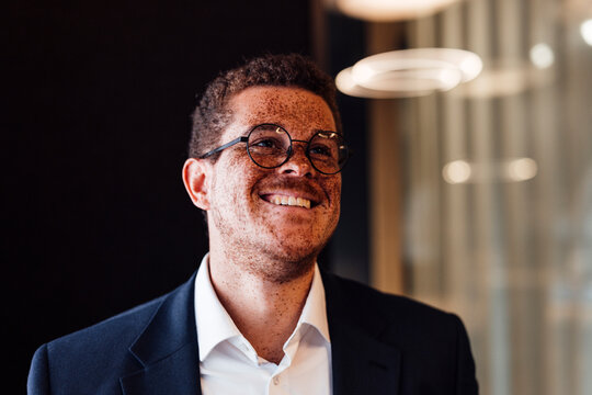 Smiling businessman with freckles shows confidence in the office