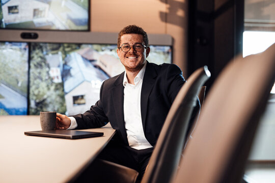 A smiling businessman holds a coffee mug in the modern office