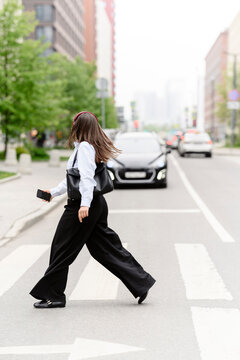 Woman crosses city street while listening to music