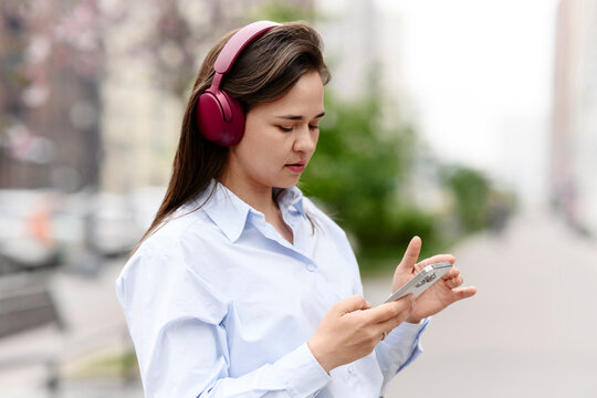 Woman uses smartphone and listens to music outdoors