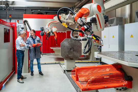 Manager and engineer inspecting industrial robot in factory