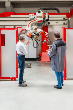 Engineer and manager inspect an industrial robot in a factory