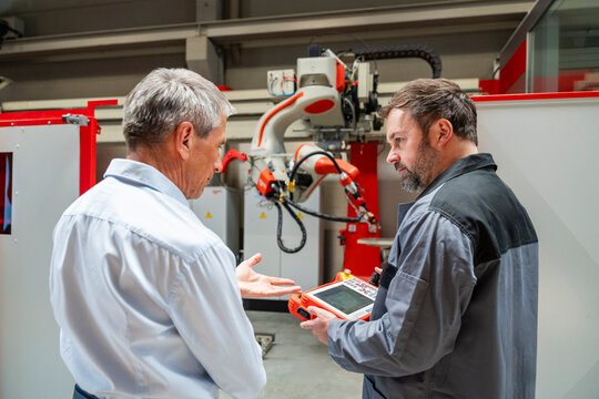 Manager and engineer discuss automation near an industrial robot