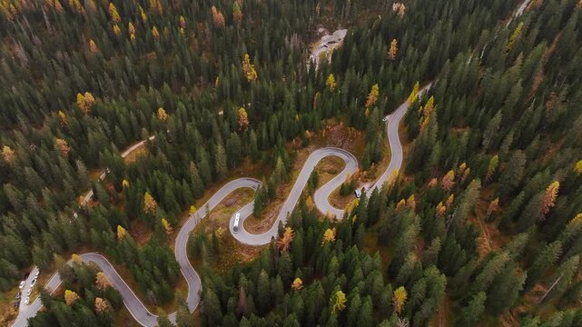 Giau Pass snake road in Italy, aerial top view of beautiful nature with bunch of green and yellow trees.