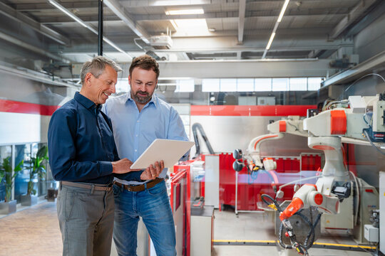 Two engineers review production on a tablet in a factory