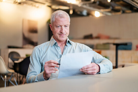Businessman reviews a document at his office desk