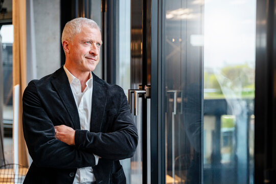 Thoughtful senior businessman looking out of office window