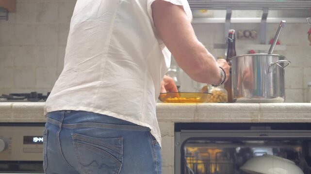 Seen from behind, a housewife spoons freshly boiled chickpeas into glass jars, preparing them for freezing to be enjoyed at a later time in a practical and resourceful home routine.
