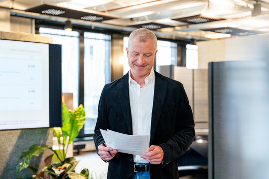 A smiling businessman reads a document in the office