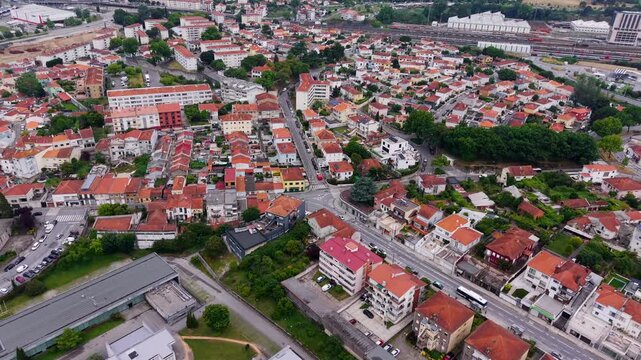 Aerial - Porto Antas neighbourhood with red rooftops a roundabout intersecting streets and railway lines beyond