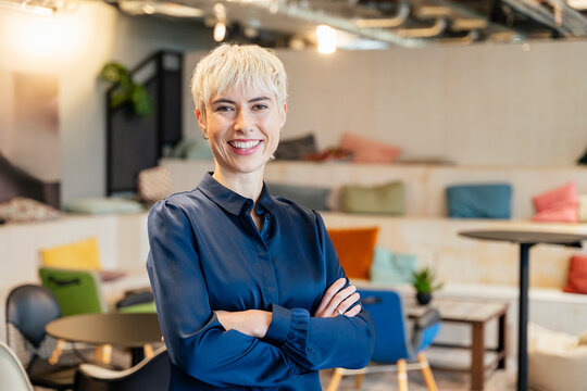 Smiling businesswoman with crossed arms standing in modern office