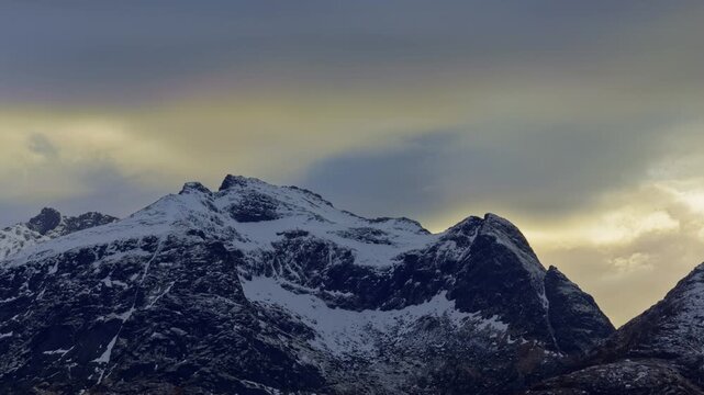 Close-up panning time-lapse: mountain peaks under heavy clouds blocking the sunlight. Lofoten Islands, Northern Norway.