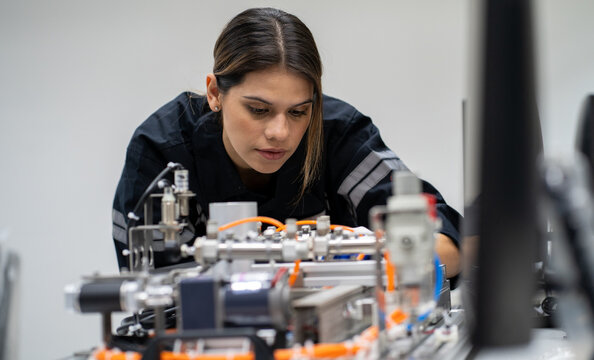 Computer science development engineer working on robotic arm connection and control at electronic futuristic technology center. Modern people training in industry 4.0 automated engineering workshop