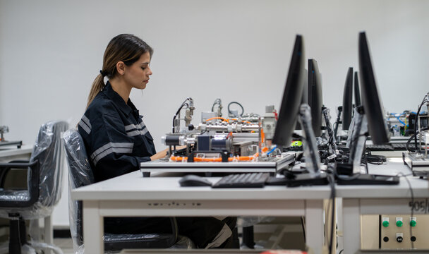 Computer science development engineer working on robotic arm connection and control at electronic futuristic technology center. Modern people training in industry 4.0 automated engineering workshop