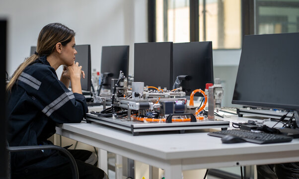 Computer science development engineer working on robotic arm connection and control at electronic futuristic technology center. Modern people training in industry 4.0 automated engineering workshop