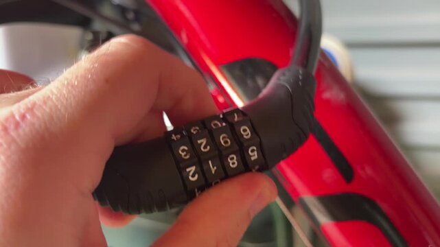 Hand Setting Combination Bike Lock On Red Bicycle Frame Close Up