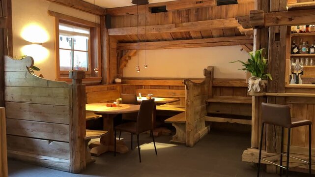 Cozy wooden restaurant interior inside a traditional Dolomites mountain lodge featuring rustic furniture, warm lighting and alpine hospitality atmosphere