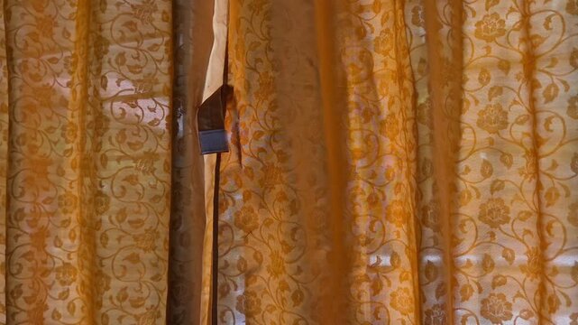 Close Up Panning Shot of Orange Floral Pattern Curtain with Sunlight Filtering Through