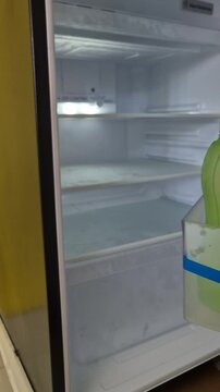 A Hand Opening an Empty and Clean Refrigerator Freezer Compartment with Purple Geometric Pattern Door