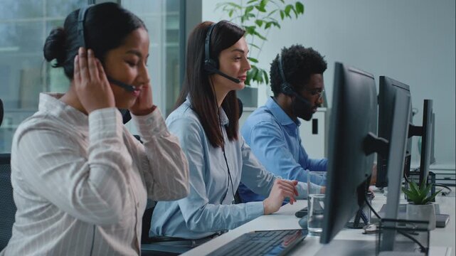 Three diversity business operators talking working in callcenter. African American woman agent talk chat with client writing notes smiling write data near multiethnic team managers work in call center