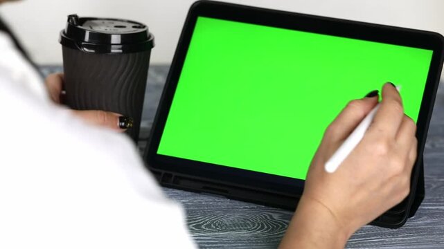 A woman's hand swipes through a tablet with a green screen