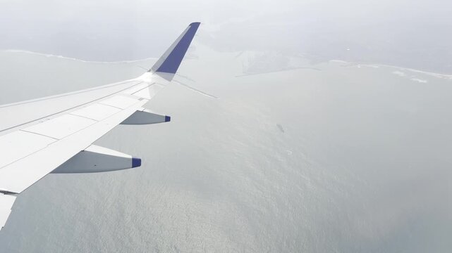 Airplane wing flying above a bright cloud layer under a dramatic blue sky, scenic aerial view from passenger window showing commercial aviation, altitude travel, freedom, journey and serene atmosphere