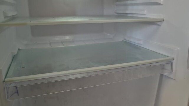 Tilt Up Shot of Empty Glass Shelves and Crisper Drawer Inside a Clean Refrigerator