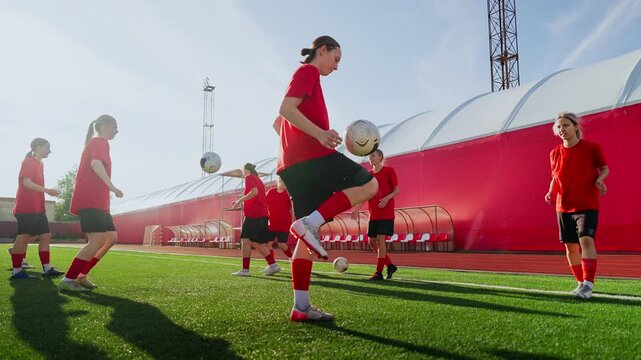 Womens soccer team practicing ball control drills on outdoor artificial turf field during sunny day training session, emphasizing teamwork, fitness, and skill development