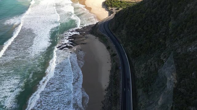 Drone view of Great Ocean Road in Victoria Australia featuring car travel beside Southern Ocean and breathtaking coastal mountain landscapes
