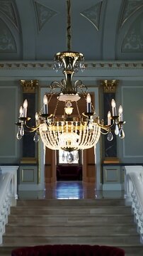 Vertical video: Pulling back camera revealing chandelier in grand hall to display crystal pendants