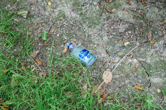 Iserlohn, Germany - June 28, 2026: Discarded Gorbatschow vodka bottle lying on cracked soil among grass and dry leaves