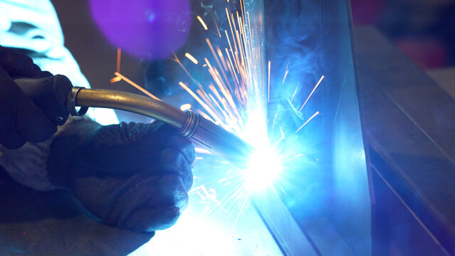 Striking close-up of bright sparks flying from heavy industrial equipment during a metalworking process. The image captures the intense heat and dynamic energy of modern manufacturing