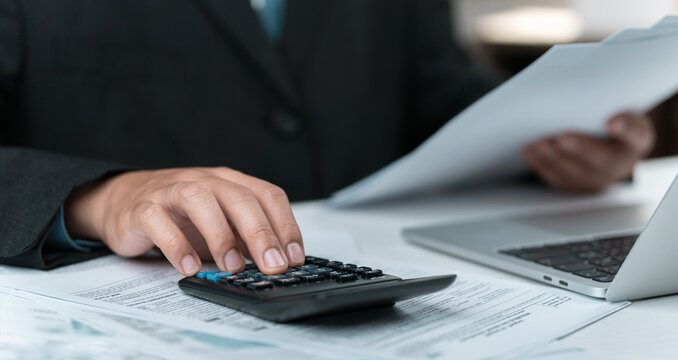 Strategic tax analysis and planning: One hand calculating, the other holding the documents, demonstrating data comparison, considering various options, and planning to maximize tax benefits.