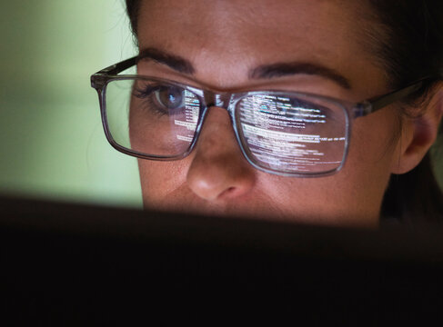Computer programmer wearing eyeglasses looking at codes